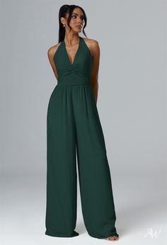 a woman wearing a dark green jumpsuit with halt neckline and wide legged legs