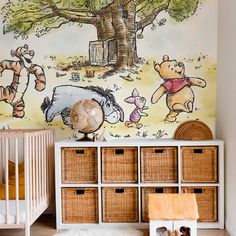 winnie the pooh wall mural in a child's room with baskets and toys