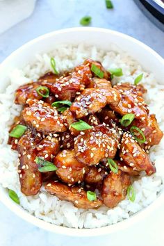 a white bowl filled with rice covered in sesame seeds and chicken wings on top of it