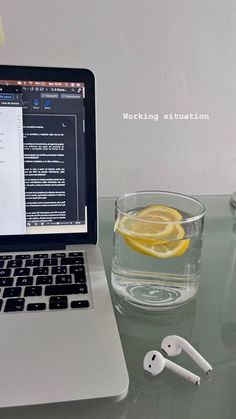 an open laptop computer sitting on top of a glass table next to a lemon slice