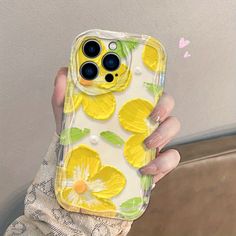 a woman holding up her phone case with yellow flowers on it