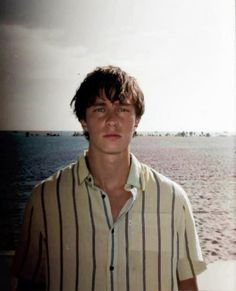 a young man standing in front of the ocean