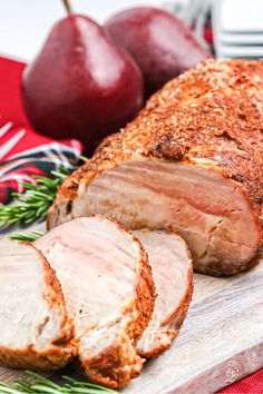 sliced pork on a cutting board with apples in the background