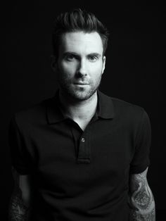 a black and white photo of a man with tattoos on his arm, wearing a polo shirt