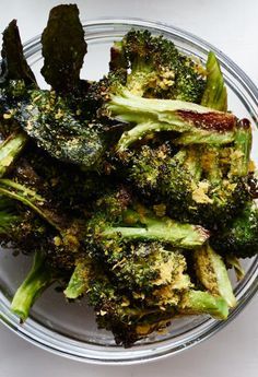 broccoli florets in a glass bowl on top of a white table