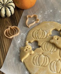 some cookies are on a table next to pumpkins and other food items that include cookie cutters