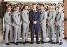 a group of men standing next to each other in front of stacks of firewood