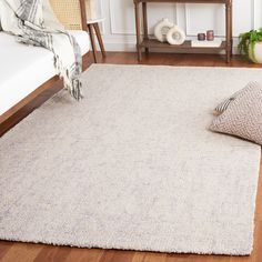 a living room area with a rug, chair and table in the background on hardwood flooring