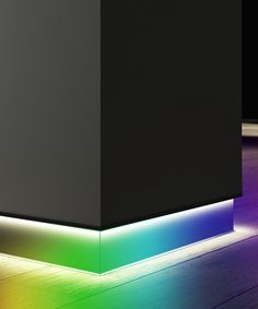 a black box sitting on top of a wooden floor next to a rainbow colored light