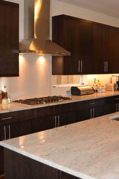 a kitchen with marble counter tops and dark wood cabinets, along with stainless steel appliances