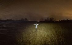 a person standing in the middle of a field at night with their arms spread out