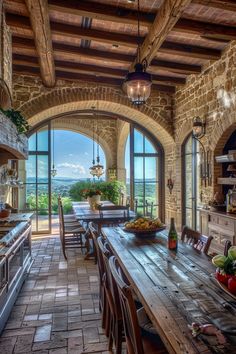 an open kitchen and dining area with stone walls, arched doorways and large windows