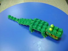 a green plastic alligator on top of a blue table