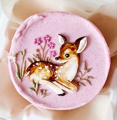 a pink cake decorated with a deer and flowers