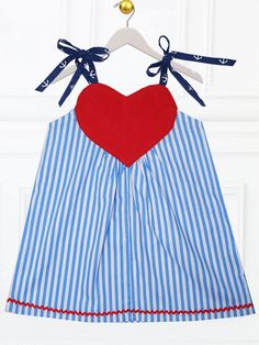 a blue and white striped dress with a red heart on the chest, hanging from a hanger