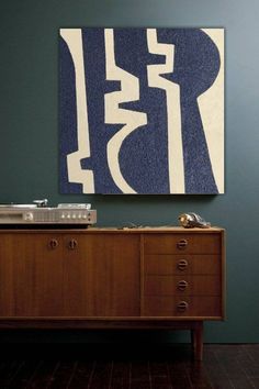 a blue and white painting hanging on the wall next to a wooden dresser with drawers