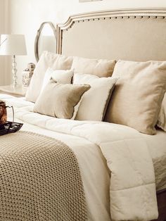 a bed with white sheets and pillows in a bedroom