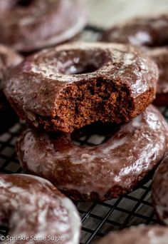 chocolate glazed donuts stacked on top of each other with one bite taken out of them