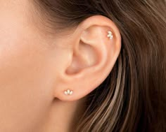 a close up of a woman's ear with three small white flowers on it