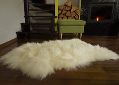 a white sheepskin rug on the floor in front of a fire place and chair