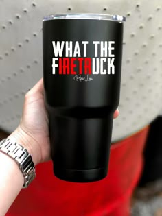 a person holding up a black cup with what the firetruck on it's side