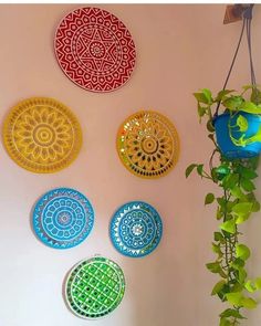 four plates are hanging on the wall next to a potted plant and some plants