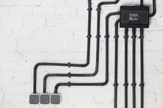 a white brick wall with black piping and electrical equipment on it's side