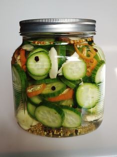 a mason jar filled with sliced cucumbers and carrots on top of seeds