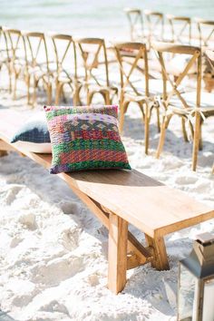 a wooden bench sitting on top of a sandy beach