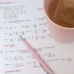 a cup of coffee sitting on top of a table next to a pen and calculator