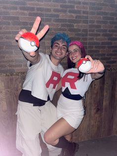 two people dressed in costumes posing for a photo with their hands up to the camera