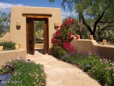 an adobe - style house with flowers in the foreground