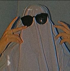 two hands holding up sunglasses to show the reflection in them's eyes while wearing a veil