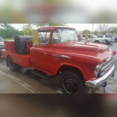 an old red truck parked in a parking lot