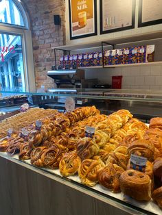 a display case filled with lots of different types of breads and pastries in front of a window