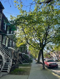 the street is lined with parked cars and apartment buildings