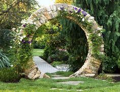 a stone arch in the middle of a garden