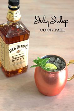 a bottle of jack daniels whiskey next to a copper mug filled with ice and garnishes