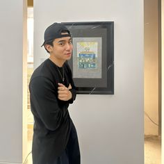 a man standing in front of a wall with a painting hanging on it's side