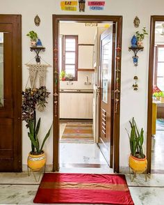 an entry way with potted plants on either side and a red rug in the middle