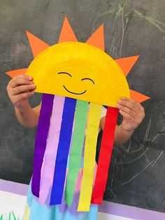 a child holding up a paper plate with a sun on it