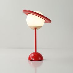 a red table lamp sitting on top of a white counter