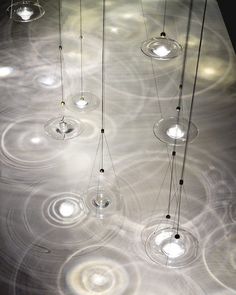 several lights hanging from strings in an art installation with circles on the ceiling and circular light bulbs suspended above them