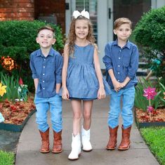 three young children are standing in front of a house wearing cowboy boots and denim outfits