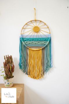 a wall hanging made out of yarn with a sun on the top and fringes around it