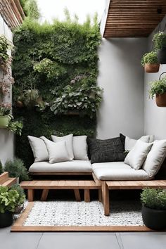 an outdoor living area with plants on the wall and couches in the corner,