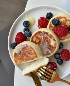 pancakes with icing, raspberries and blueberries on a white plate