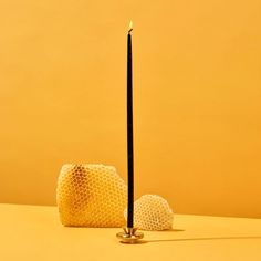 a candle is sitting on a table next to two balls with a black stick sticking out of it