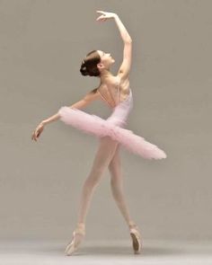 a ballerina in a pink tutu and leotard with her arms stretched out