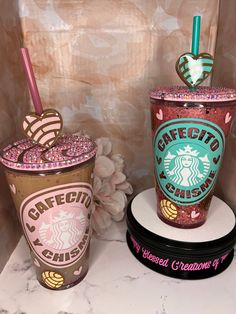 two starbucks drink cups are sitting on a marble counter with pink and blue glitters